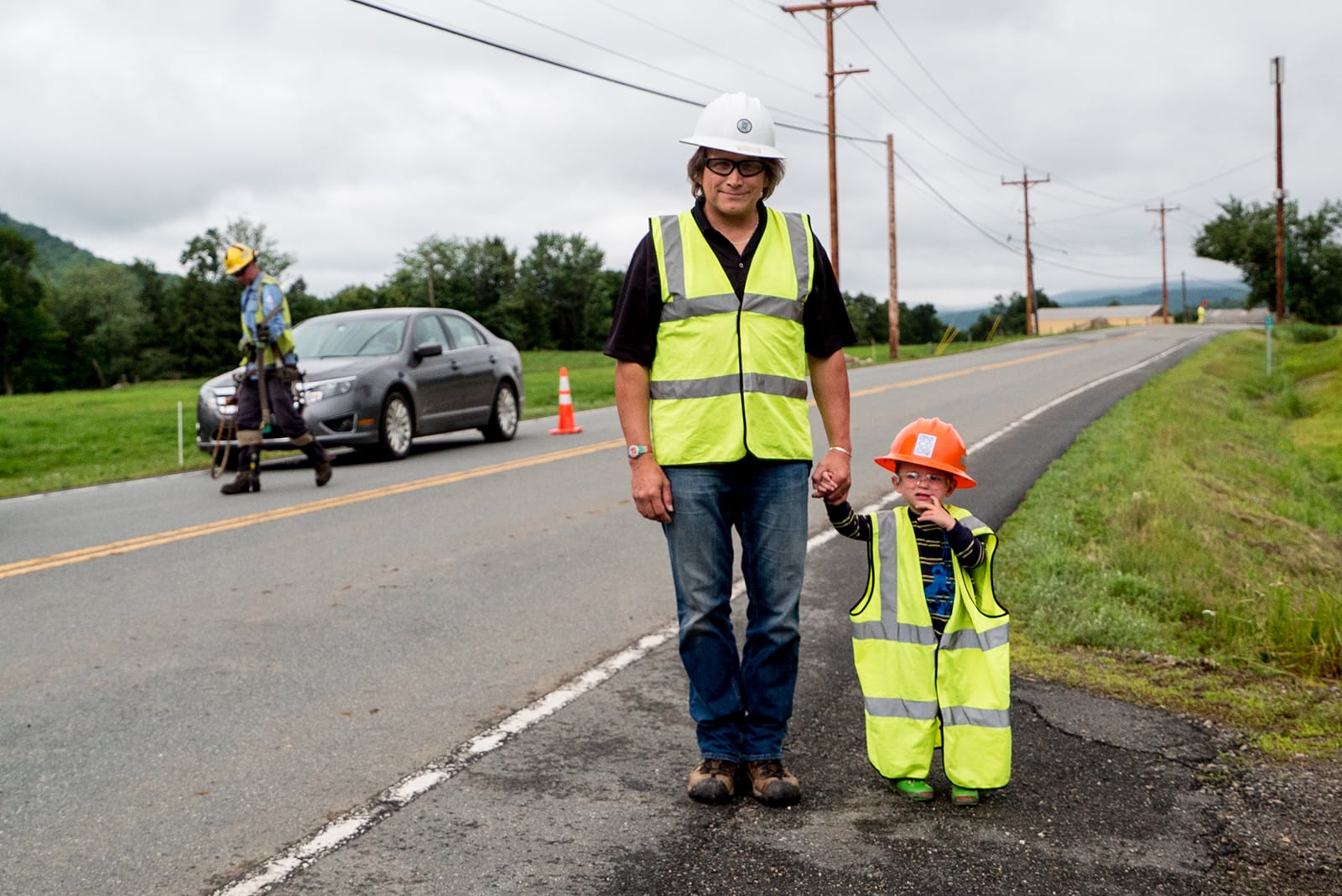 Man and child in vests on side of road